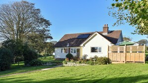 A house with a sloped roof, solar panels, and a well-maintained lawn. - 3 bedroom accommodation in Membury, near Axminster (Membury, near Axminster)