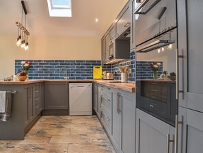 A modern kitchen with grey cabinets, a dishwasher, a yellow toaster, and a tiled backsplash.