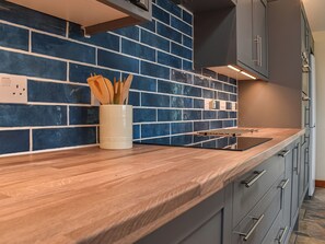 A kitchen with a blue-tiled backsplash, wooden countertop, and modern cabinetry.