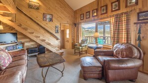 A cozy cabin interior with a wooden staircase, leather furniture, and framed artwork on the walls. - Creede Cabin - Dogs Welcome - Amazing Views - Large Deck (Creede)