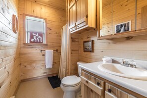 A wooden cabin bathroom with a toilet, sink, and a window with a towel hanging on the wall. - Creede Cabin - Dogs Welcome - Amazing Views - Large Deck (Creede)