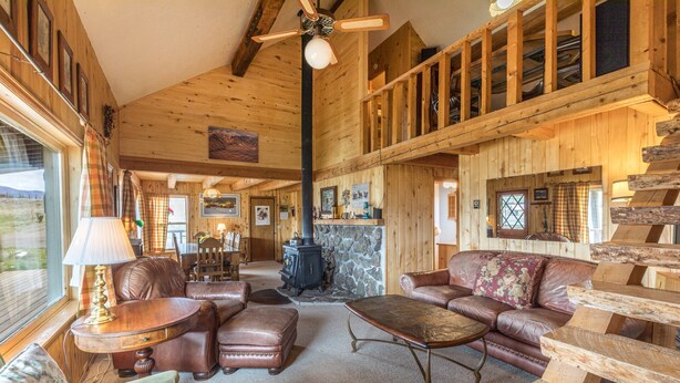A cozy log cabin interior with a fireplace, leather furniture, and a wooden staircase. - Creede Cabin - Dogs Welcome - Amazing Views - Large Deck (Creede)
