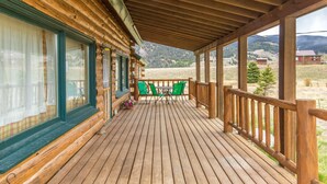 A wooden cabin with a covered porch, green chairs, and a view of mountains. - Creede Cabin - Dogs Welcome - Amazing Views - Large Deck (Creede)