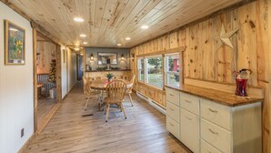 Un interior de madera con comedor, cocina y ventanas grandes.