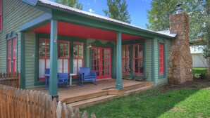 A house with a porch, red-framed windows, and a stone chimney. - Historic Home | Pet Friendly | Walkable to Downtown (Creede)