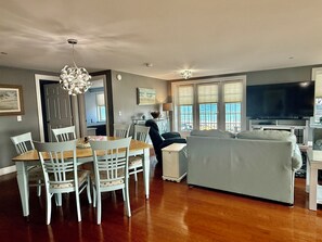 Un salon comprenant un canapé, une table à manger et des chaises. On y trouve également un téléviseur et un lustre.
