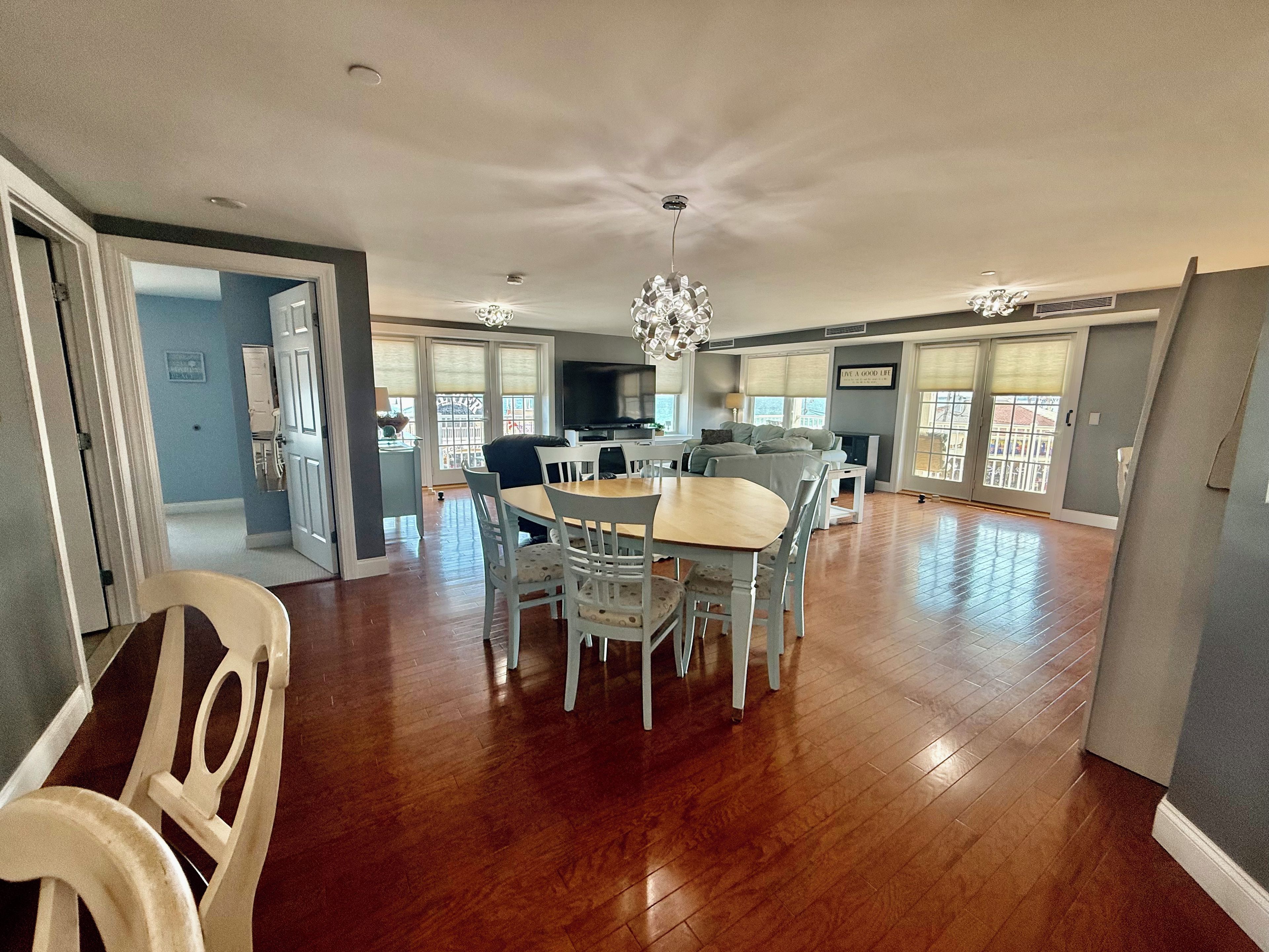 A spacious living area with a dining table, chairs, a chandelier, and a fireplace.