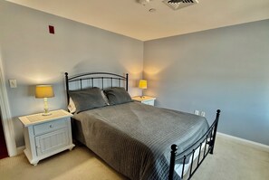 Une chambre avec un lit simple, deux tables de chevet et deux lampes.