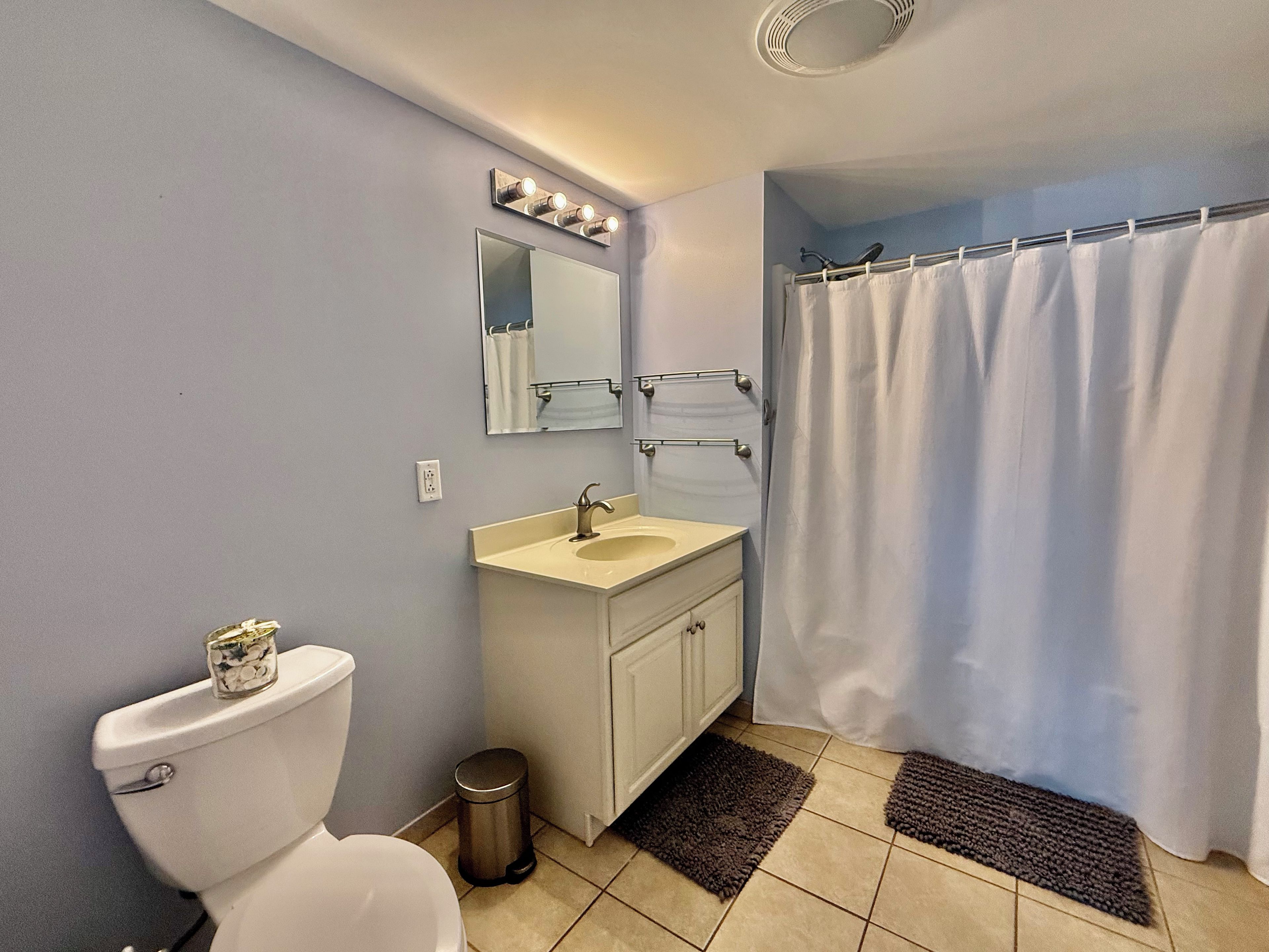 A bathroom with a toilet, sink, mirror, and shower curtain.