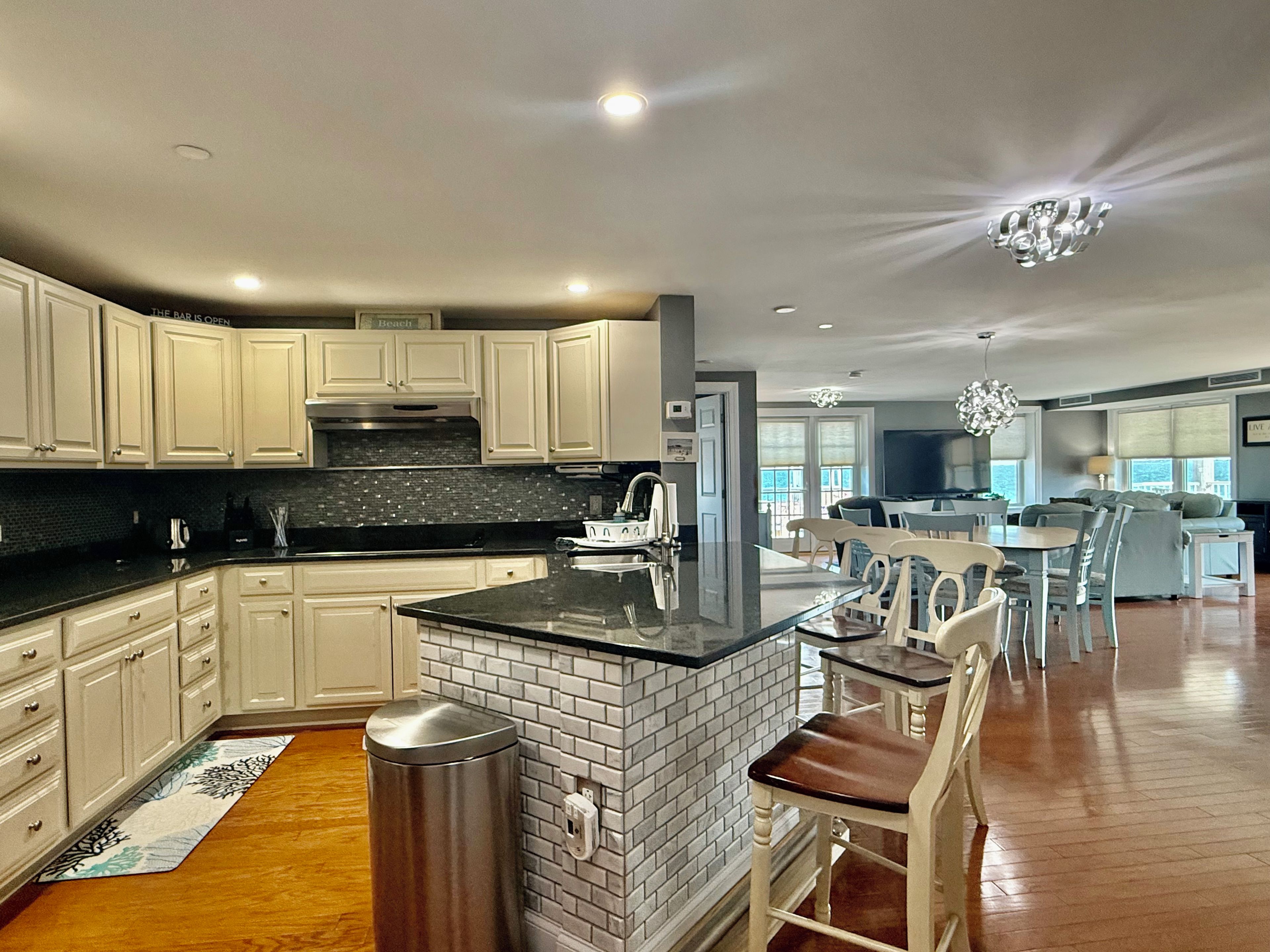 A modern kitchen with white cabinetry, a black countertop, and a brick backsplash.
