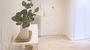 A hallway with a white door, a plant on a white shelf, and a woven basket.