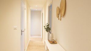 A hallway with a white console table, a potted plant, and decorative wall art.