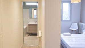 A modern bedroom with a large bed, a bedside table, a chair, and a window.
