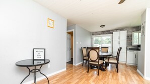 A spacious kitchen with white cabinets and a dining area with a round table and chairs. - 🏖 Sandy Hook: 2 Queens, Pet Friendly, One Min to Beach, Ice Fishing and Snaks (Sandy Hook)