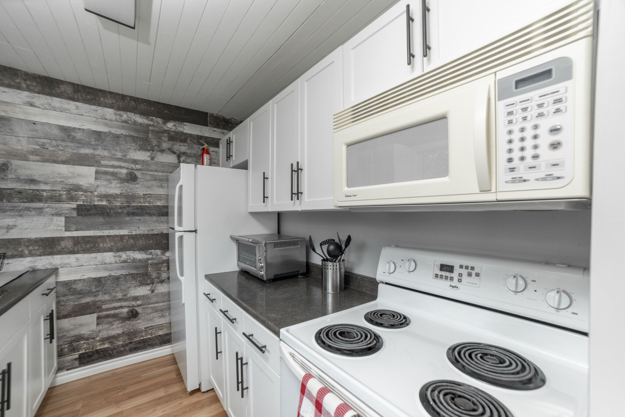 A modern kitchen with white appliances, a wood-textured wall, and a compact layout.