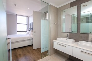 Un baño moderno con cabina de ducha de vidrio, tocador doble y un espejo grande.