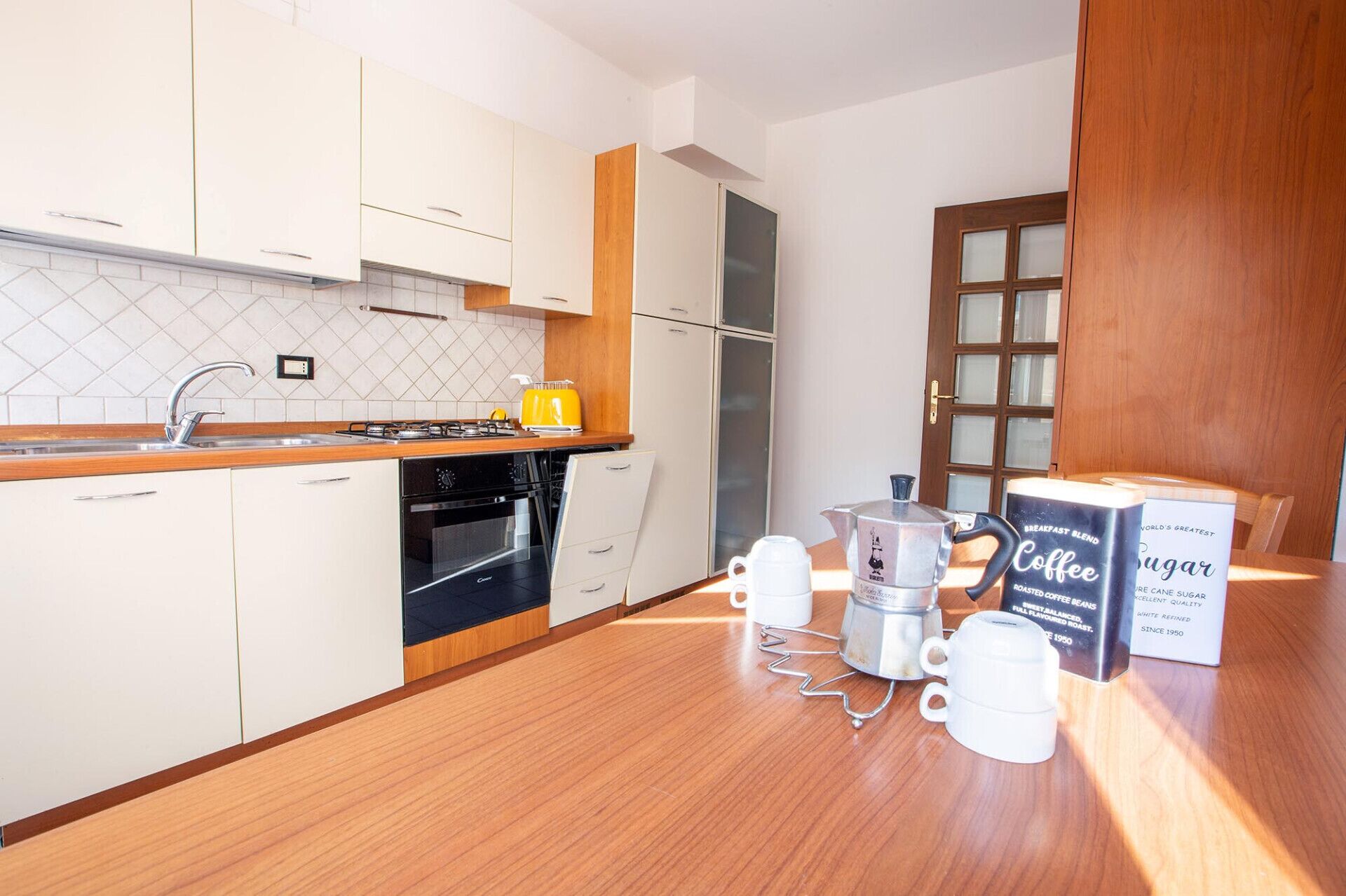 A modern kitchen with white cabinets, a wooden countertop, a gas stove, and a coffee maker.