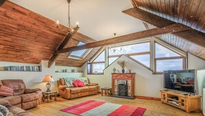 Ein Loft-Wohnzimmer mit Kamin, Fernseher und Bücherregalen.