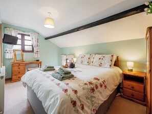 A bedroom with a bed, bedside table, dresser, and a desk with a chair.