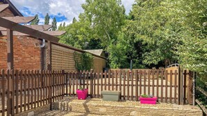 A fenced backyard with a brick building, stone walls, and two potted plants. - Purbeck View - UK36320 (Holly Hedge Farm)
