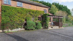 A brick house with a gravel driveway and a wooden pergola. - Purbeck View - UK36320 (Holly Hedge Farm)