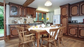 A kitchen with wooden cabinets, a dining table with chairs, and a refrigerator. - Coachman's lodge - UK35952 (Kingsbridge)