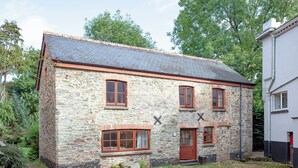 A stone building with a tiled roof, multiple windows, and a door. - Coachman's lodge - UK35952 (Kingsbridge)