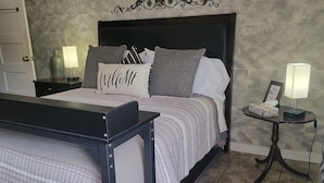 A neatly arranged bedroom with a bed, bedside tables, and a nightstand. - THE COZY COTTAGE, A Great place to hang your hat. (Post)
