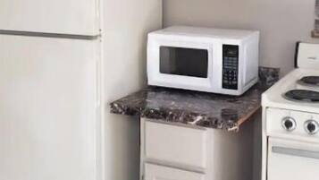 Une cuisine avec des armoires blanches, un réfrigérateur blanc, un four à micro-ondes et une cuisinière.