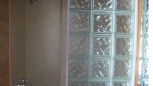 A shower with a glass door, a metal showerhead, and a glass shower caddy. - THE COZY COTTAGE, A Great place to hang your hat. (Post)