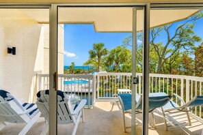 A balcony with white chairs and a table, overlooking a pool and a view of the ocean. - 206 Barrington Arms- OCEANFRONT and BEAUTIFUL (Hilton Head Island)