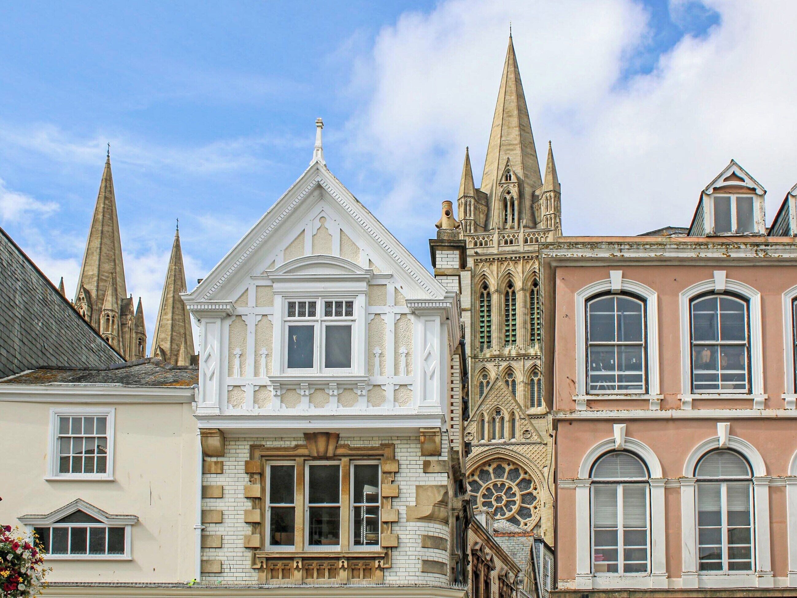 A row of historic buildings with varied architectural styles, including pointed spires and ornate window designs.