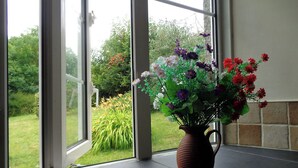 Ein Fenster mit Blick auf einen Garten und einer Blumenvase auf einem Fensterbrett.
