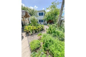 A house with a garden, a thatched structure, and a tall tree. - Sealy Suites B Historic East End - Walk to Beach, UTMB & Strand (Galveston)