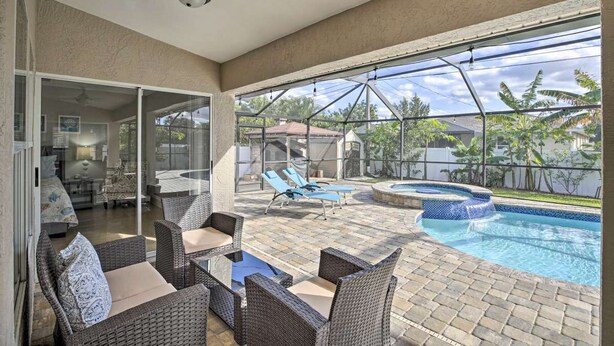 An outdoor patio with wicker furniture, a swimming pool, and a hot tub. - Private Home w/ fence/SPA/Pool & Screened Lanai! (Cape Coral)