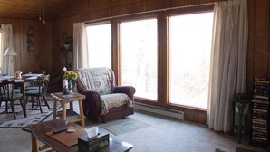 A cozy cabin interior with a wooden interior, a sofa, a dining table, and a fireplace.