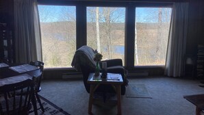 A room with a large window, a dining table, and a chair.