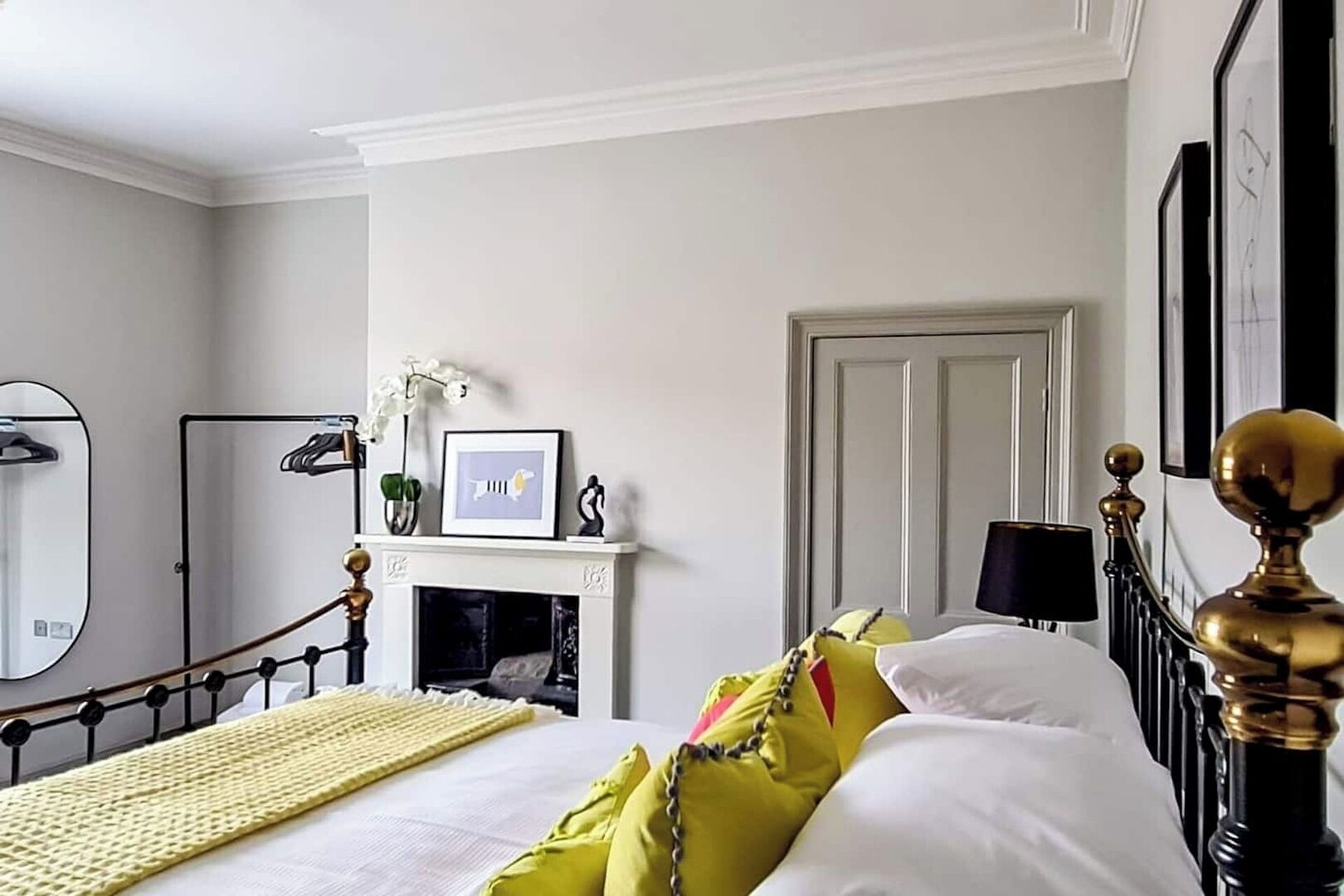 A bedroom with a bed, a fireplace, a mirror, and a door.