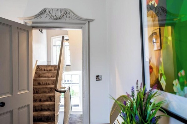Una escalera con una pared blanca y una puerta que da a otra habitación.
