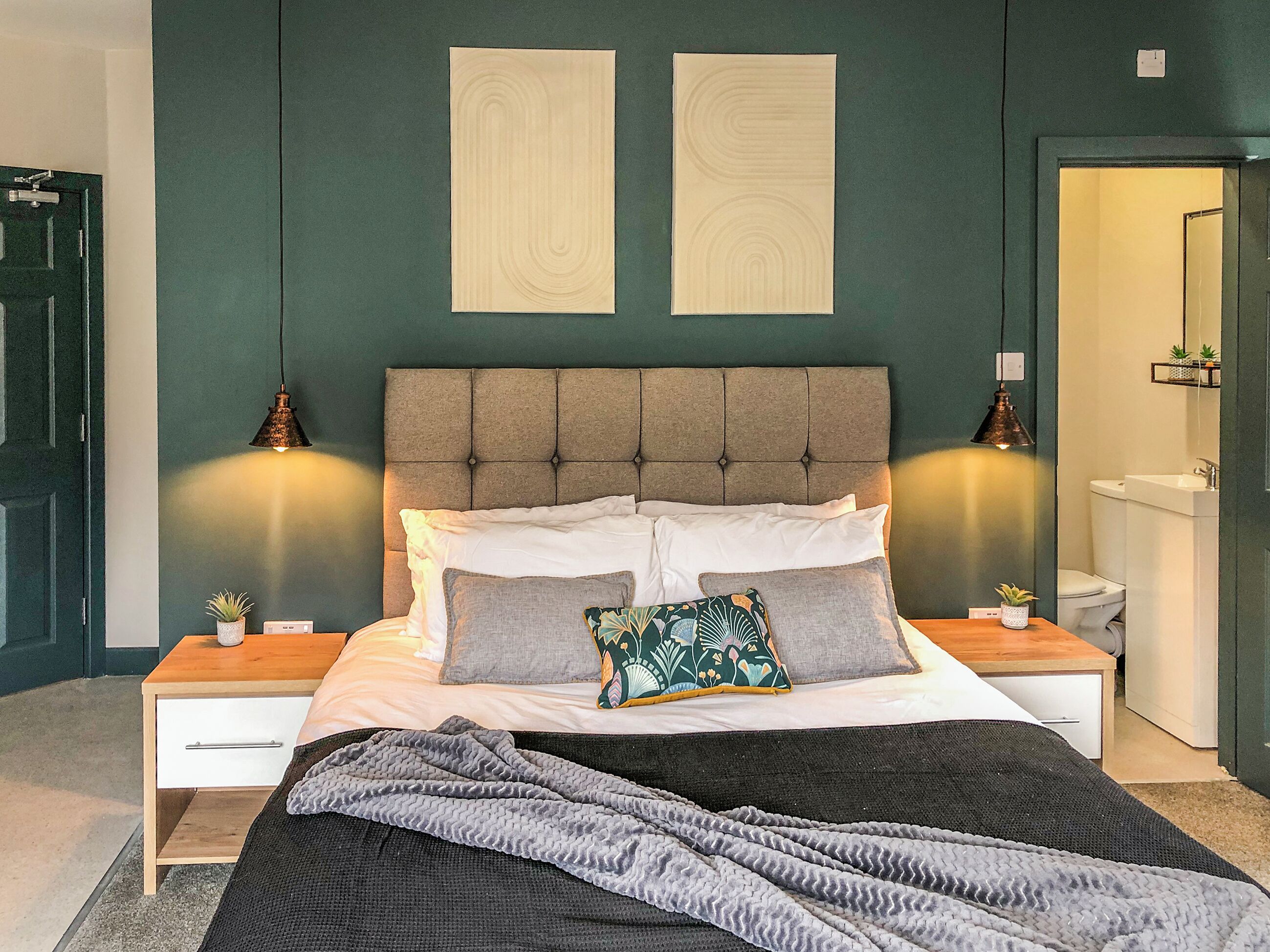 Ein Schlafzimmer mit einem Bett, zwei Nachttischen, einer Kommode, einem Spiegel und einer Tür.