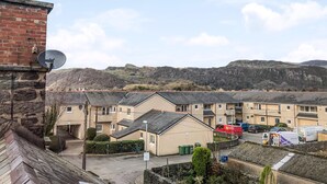 A residential area with terraced houses, a street, and a hilly landscape in the background.