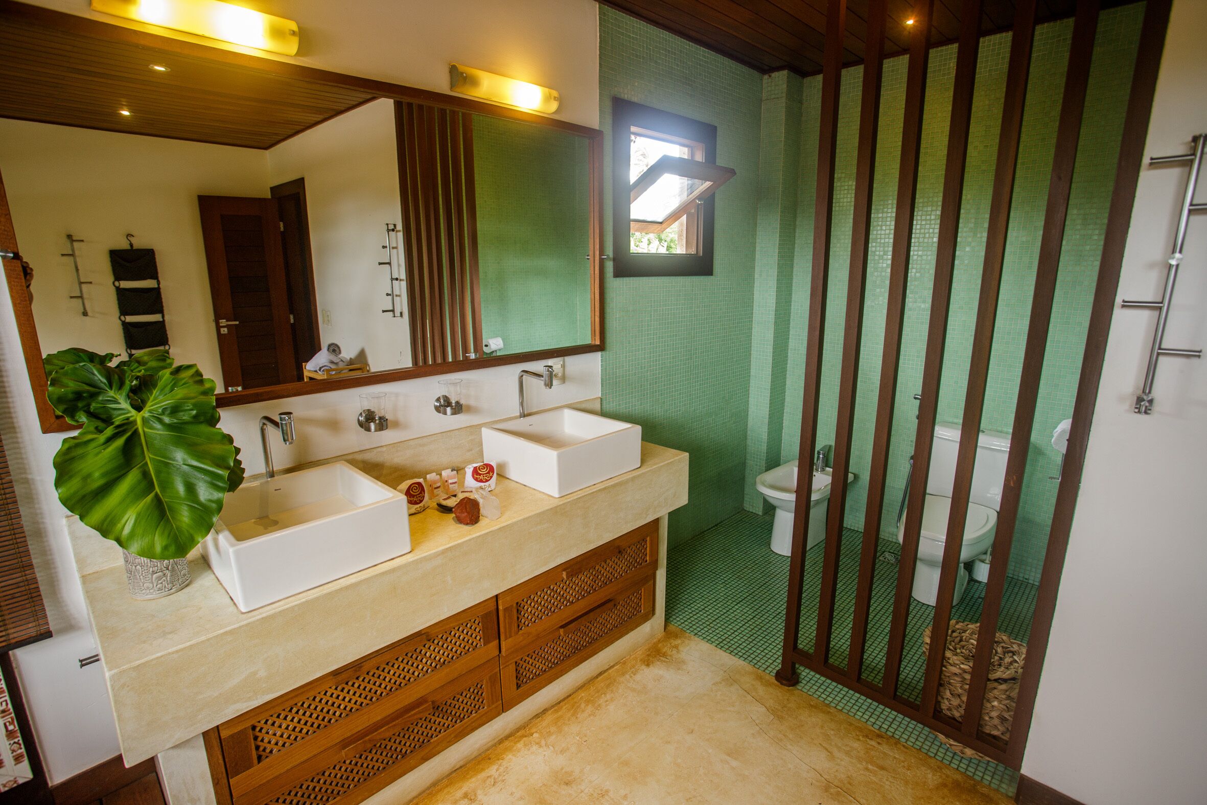 A bathroom with a double sink vanity, a large mirror, and a green-tiled shower enclosure.