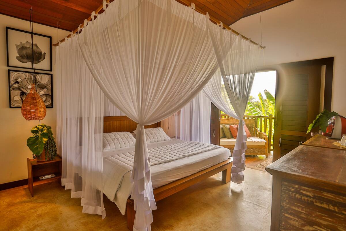 A bedroom with a canopy bed, wooden headboard, and a view of the outdoors.
