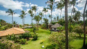 A tropical resort with a pool, palm trees, and a thatched-roof hut. - Hara Pousada e SPA (São Miguel do Gostoso)