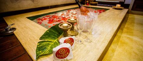 A spa reception area with a marble counter, two spa towels, a bottle of champagne, and candles.