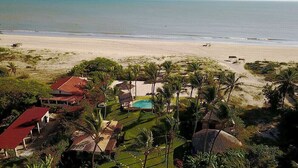 A beachfront property with a swimming pool, palm trees, and a beach. - Hara Pousada e SPA (São Miguel do Gostoso)
