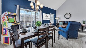 A dining area with a table set for four, a chandelier, and a view of the outside. - Bright and Gorgeous! Fish across the street - Lake Access in Branson! (Branson)