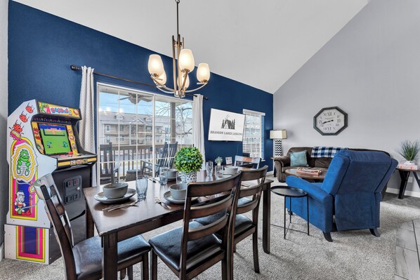 A dining area with a table set for four, a chandelier, and a view of the outside. - Bright and Gorgeous! Fish across the street - Lake Access in Branson! (Branson)