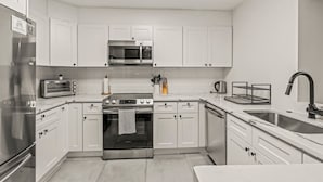 Eine moderne Küche mit weißen Schränken, Edelstahlgeräten und einem schwarzen Backofen.