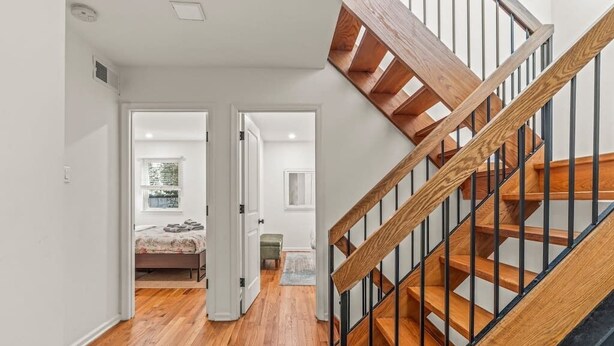 Eine Treppe mit Holzboden und schwarzen Geländern, die zu einer oberen Etage führt.